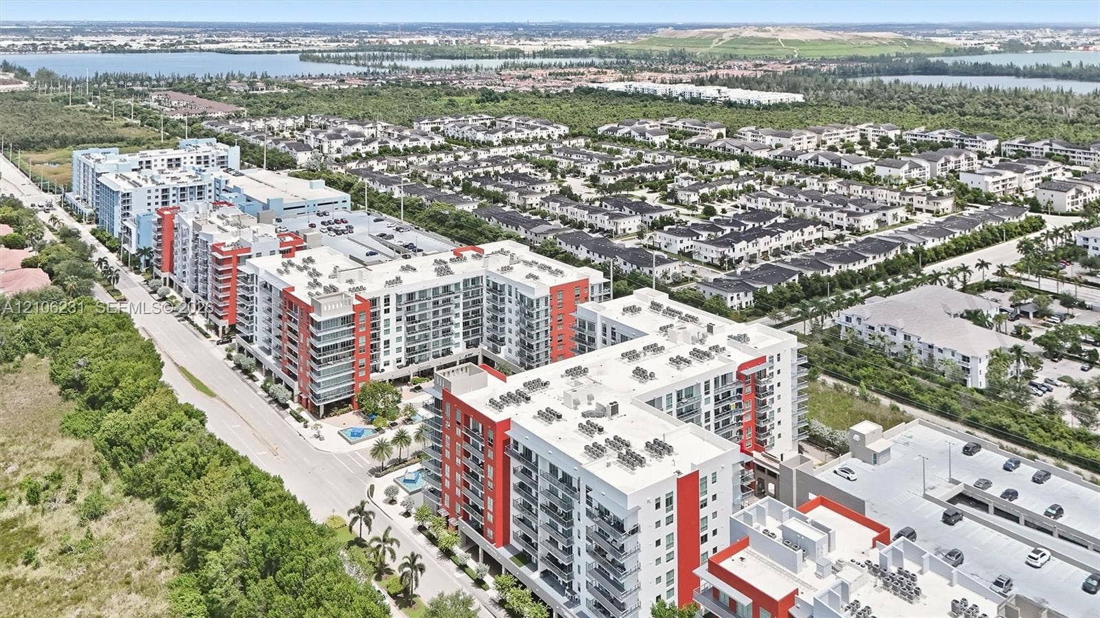 7875 NW 107th Avenue, #802, Doral, FL 33178 Aerial perspective of a multi-story residential complex featuring modern architecture, structured parking facilities, balcony units, and landscaped grounds