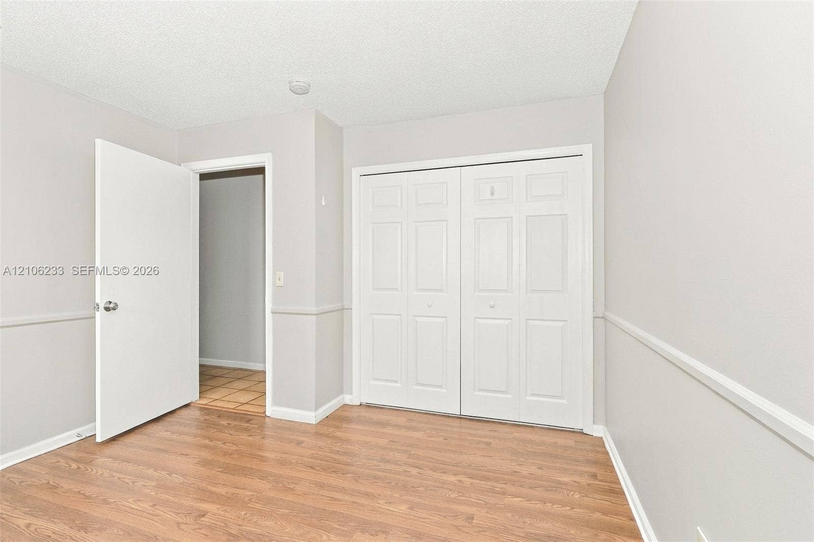 132 Santander Court, Royal Palm Beach, Royal Palm Beach, FL 33411 Room featuring wood-finish flooring, chair rail molding, and a double-door closet with paneled detailing