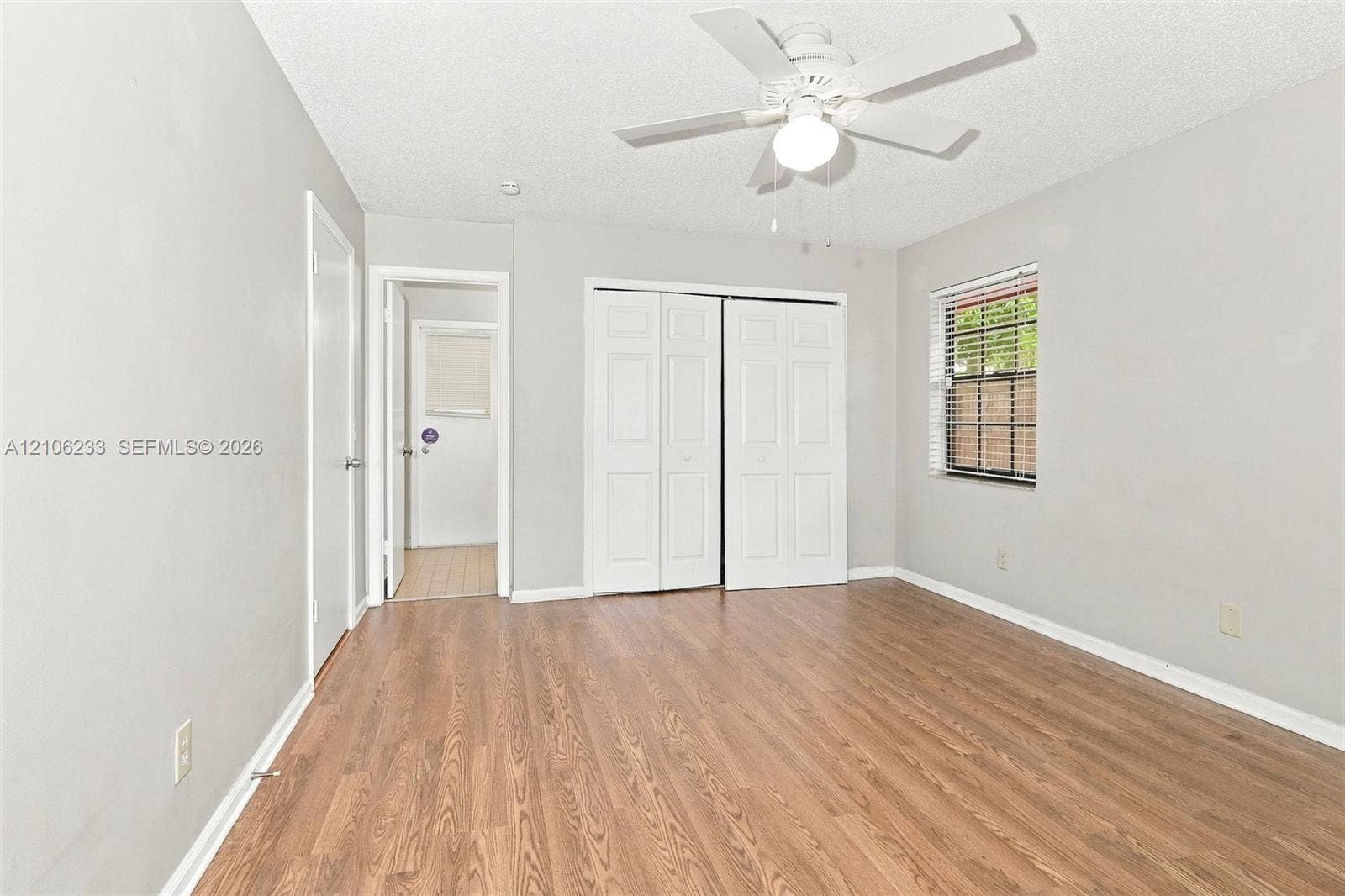132 Santander Court, Royal Palm Beach, Royal Palm Beach, FL 33411 Wood-finish flooring, white bifold closet doors, neutral wall paint, and a ceiling fan with integrated lighting