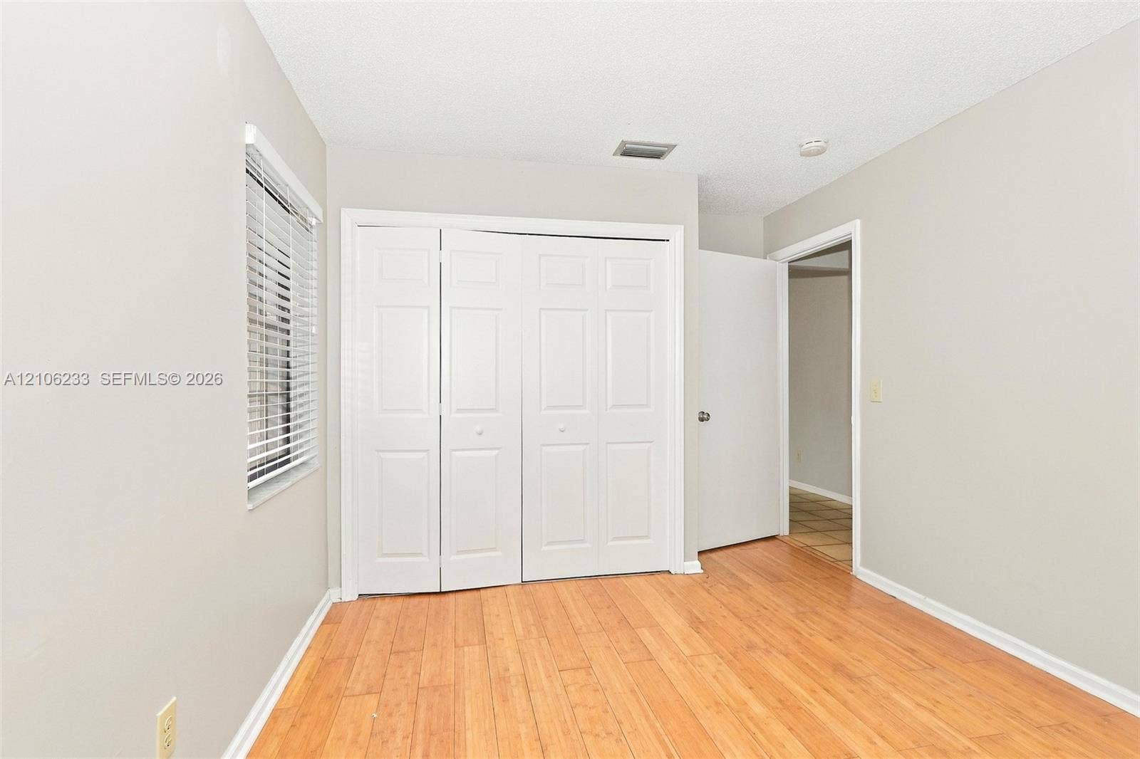 132 Santander Court, Royal Palm Beach, Royal Palm Beach, FL 33411 Wood-finish flooring, neutral wall tones, multi-panel bi-fold closet doors, and horizontal window blinds