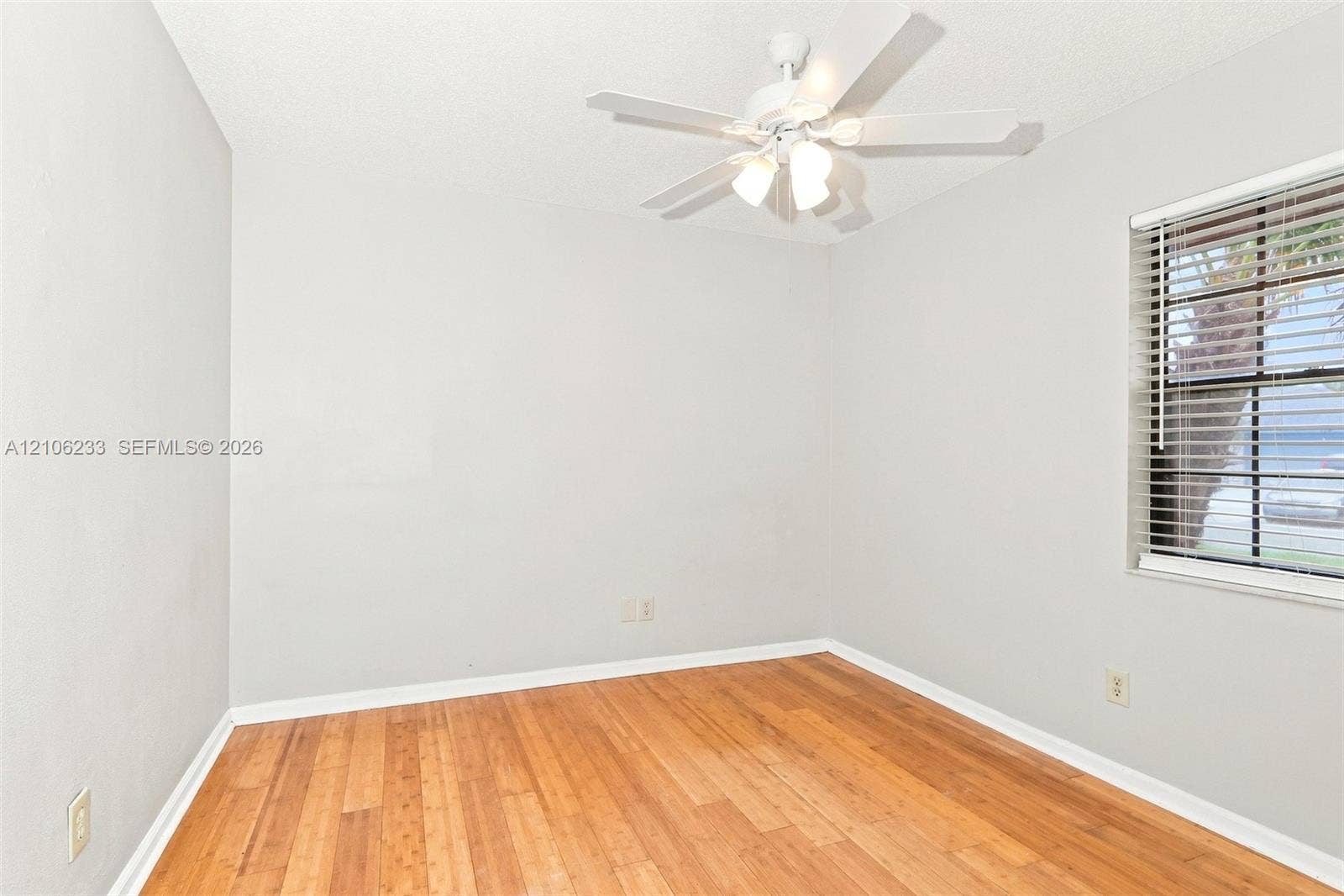 132 Santander Court, Royal Palm Beach, Royal Palm Beach, FL 33411 Neutral interior featuring wood-finish flooring, a ceiling-mounted light fixture with a fan, and a multi-pane window with horizontal blinds