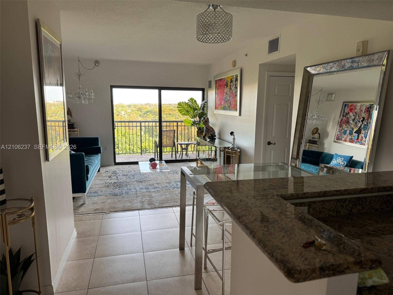 3530 SW 22nd Street, #706, Miami, Miami, FL 33145 Open-concept floor plan featuring a stone-surface breakfast bar, ceramic tile flooring, a drum-style pendant light fixture, and large sliding glass doors opening to a private balcony