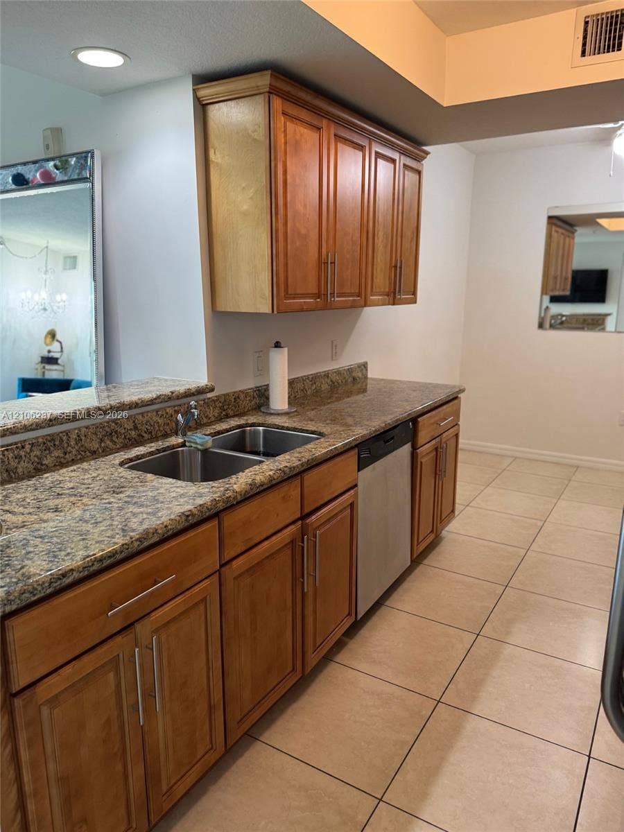 3530 SW 22nd Street, #706, Miami, Miami, FL 33145 Kitchen featuring warm-tone wood cabinetry, stone-surface countertops, stainless steel dual-basin sink, integrated dishwasher, and tile flooring