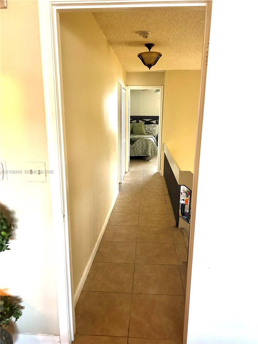 2554 N 38th Avenue, Hollywood, FL 33021 Hallway featuring tile flooring, ceiling-mounted light fixture, and black metal railing
