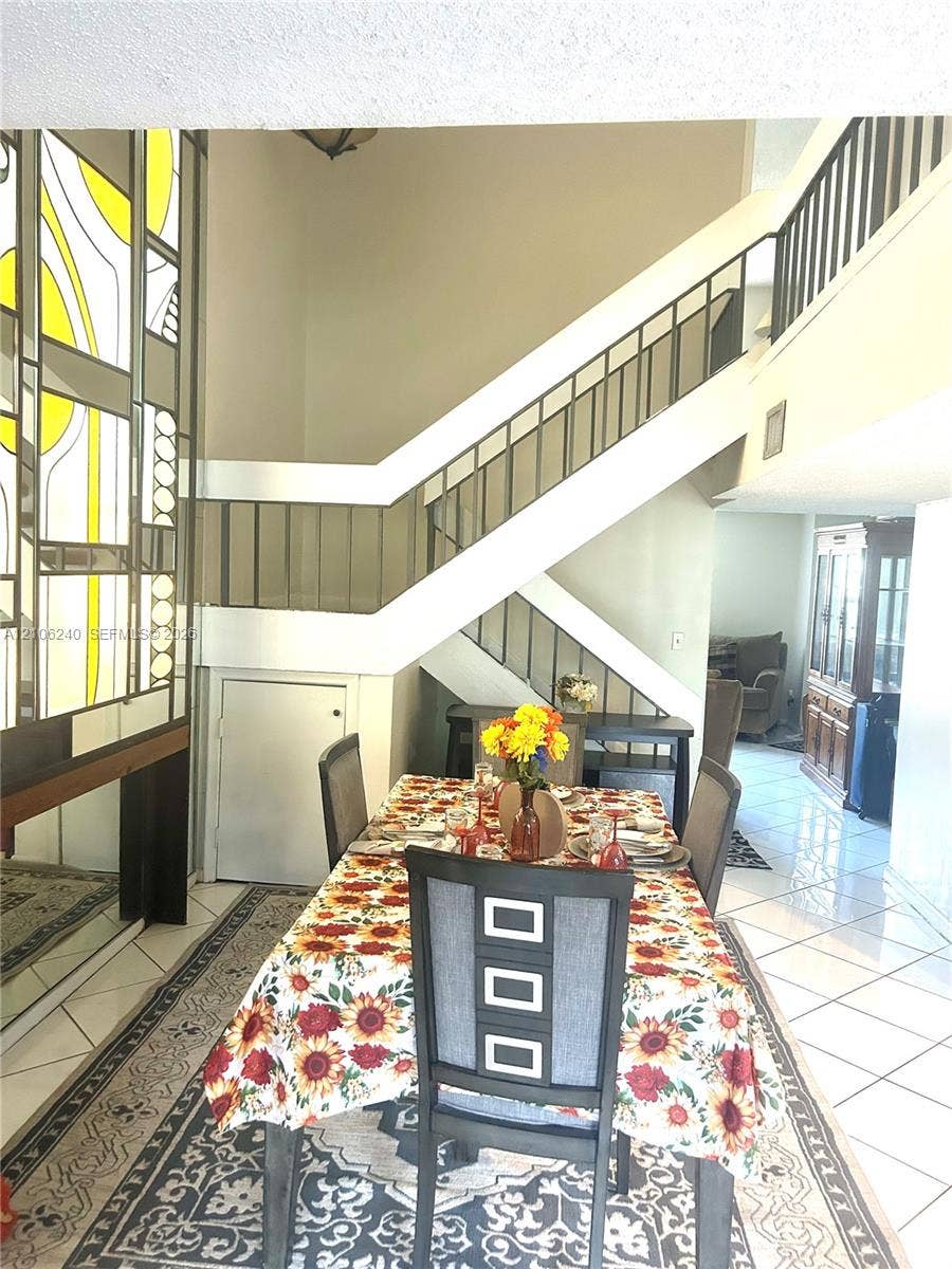 2554 N 38th Avenue, Hollywood, FL 33021 Staircase featuring a geometric metal railing, decorative stained-glass window panel, and high-gloss tile flooring