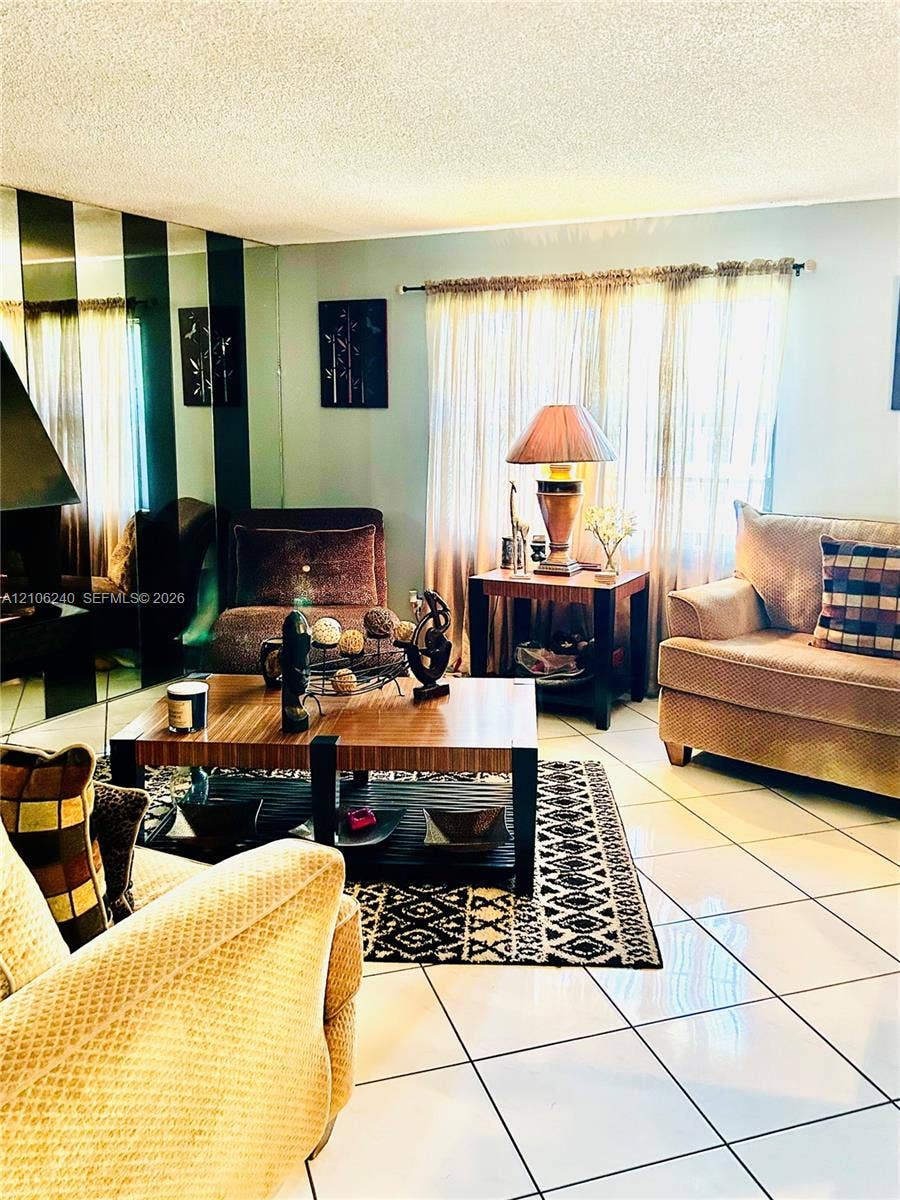 2554 N 38th Avenue, Hollywood, FL 33021 Room interior featuring floor-to-ceiling mirrored wall panels, neutral tile flooring, and a stone-surround fireplace