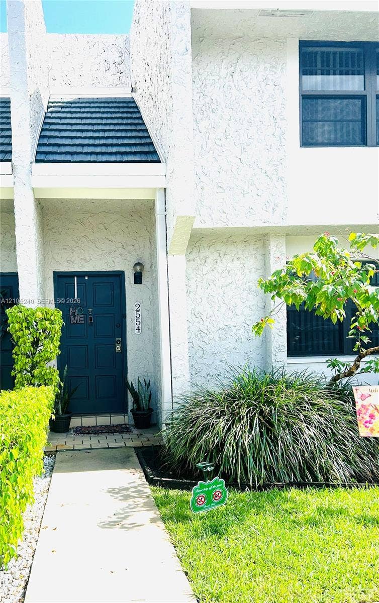 2554 N 38th Avenue, Hollywood, FL 33021 Stucco exterior with a paneled front entry door, dark-toned shingle accents, and a concrete walkway