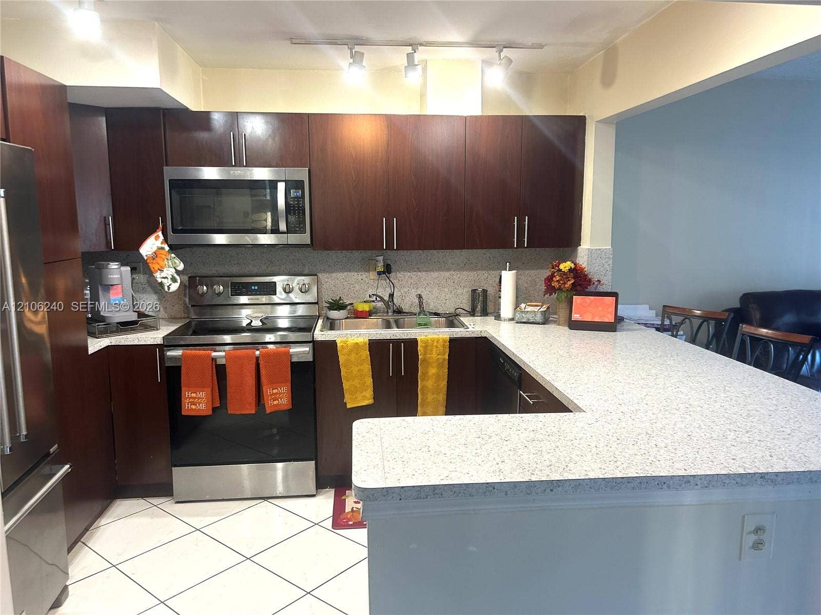 2554 N 38th Avenue, Hollywood, FL 33021 Kitchen featuring dark wood-finish cabinetry, speckled solid-surface countertops, stainless steel appliances, double-basin sink, and track lighting