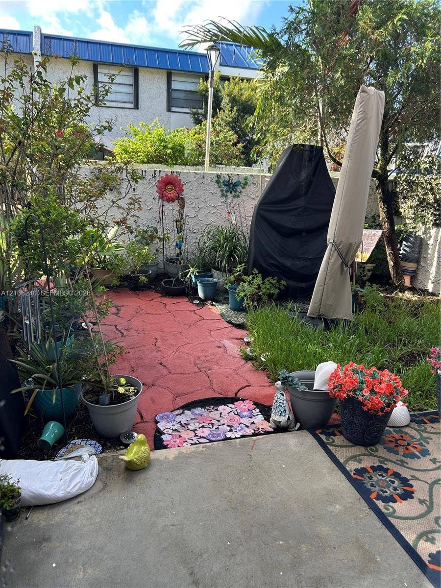 2554 N 38th Avenue, Hollywood, FL 33021 Enclosed courtyard featuring a red decorative stone-patterned patio, textured stucco privacy wall, and mature landscaping