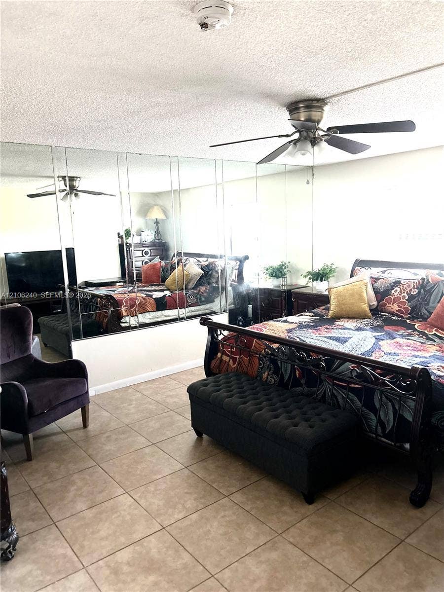 2554 N 38th Avenue, Hollywood, FL 33021 Full-wall mirrored accent, ceiling fan with integrated lighting, and neutral-toned tile flooring