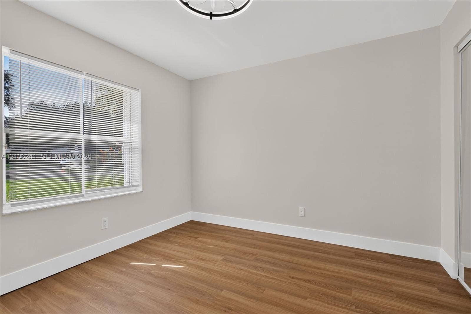 9407 SW 18th Street, Miramar, FL 33025 Neutral interior featuring wood-finish flooring, a multi-pane window with horizontal blinds, a contemporary drum-style ceiling light fixture, and mirrored closet doors