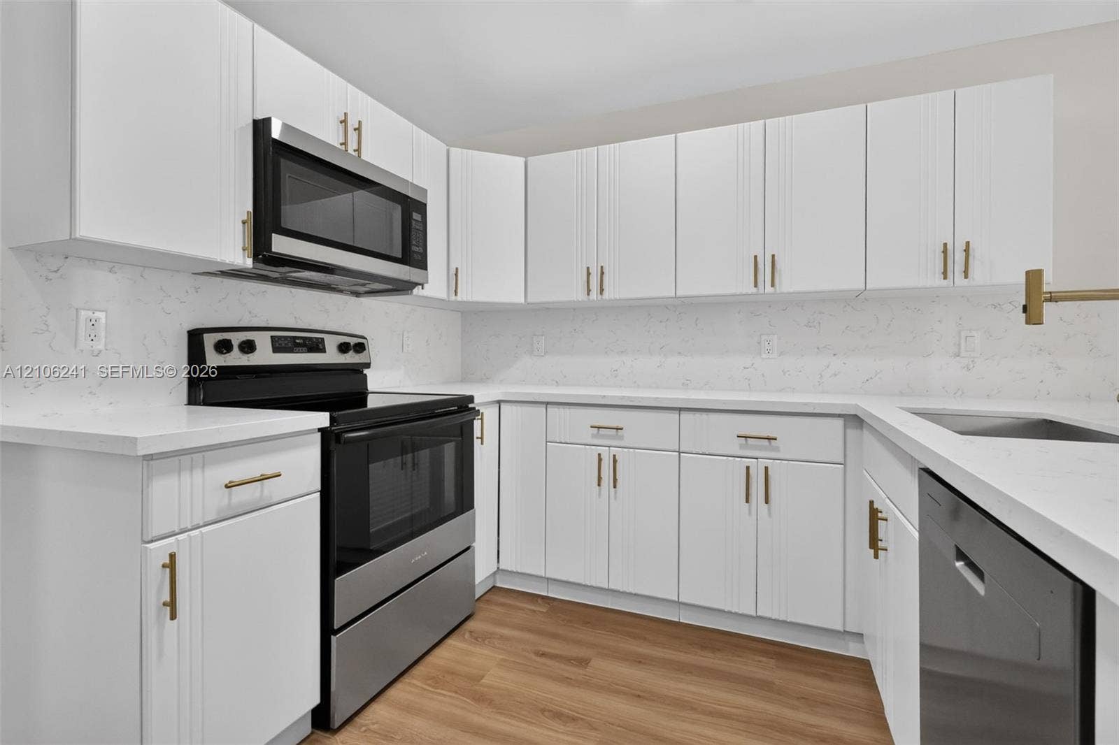 9407 SW 18th Street, Miramar, FL 33025 Kitchen featuring white shaker-style cabinetry, quartz countertops, full-height stone-patterned backsplash, stainless steel appliances, and wood-finish flooring
