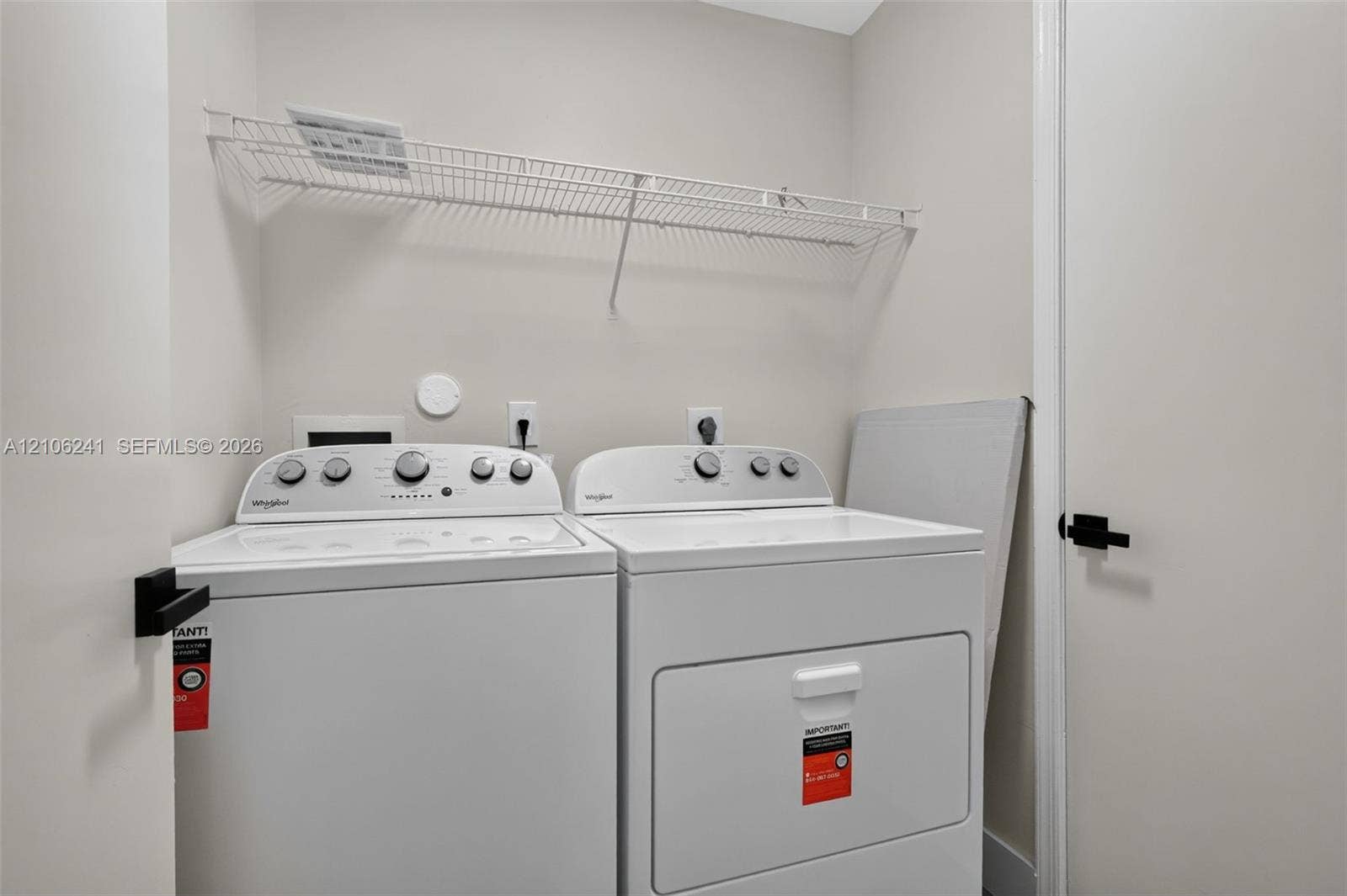 9407 SW 18th Street, Miramar, FL 33025 Laundry area featuring white top-load washer and dryer, mounted wire shelving, and matte black door hardware