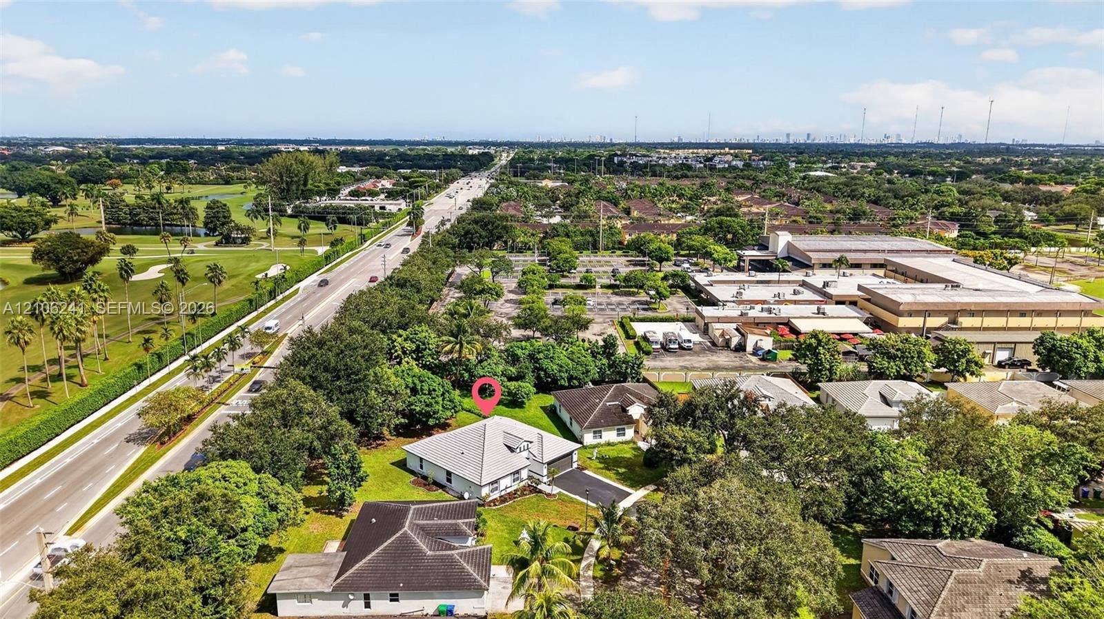 9407 SW 18th Street, Miramar, FL 33025 Aerial perspective of a detached single-story residence featuring a hip roof, attached garage, paved driveway, and established landscaping