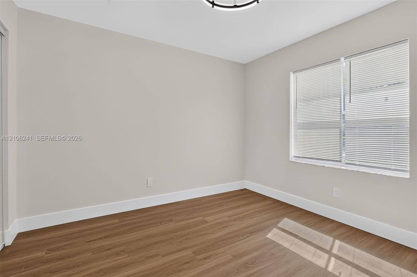 9407 SW 18th Street, Miramar, FL 33025 Neutral-toned walls, wood-finish flooring, a window with horizontal blinds, and a circular LED flush-mount ceiling light