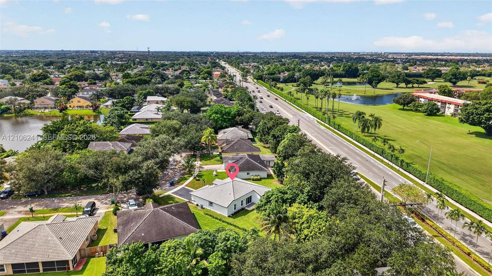 9407 SW 18th Street, Miramar, FL 33025 Aerial perspective of a single-story residence featuring a hipped roofline, paved driveway, expansive lawn, and mature canopy trees