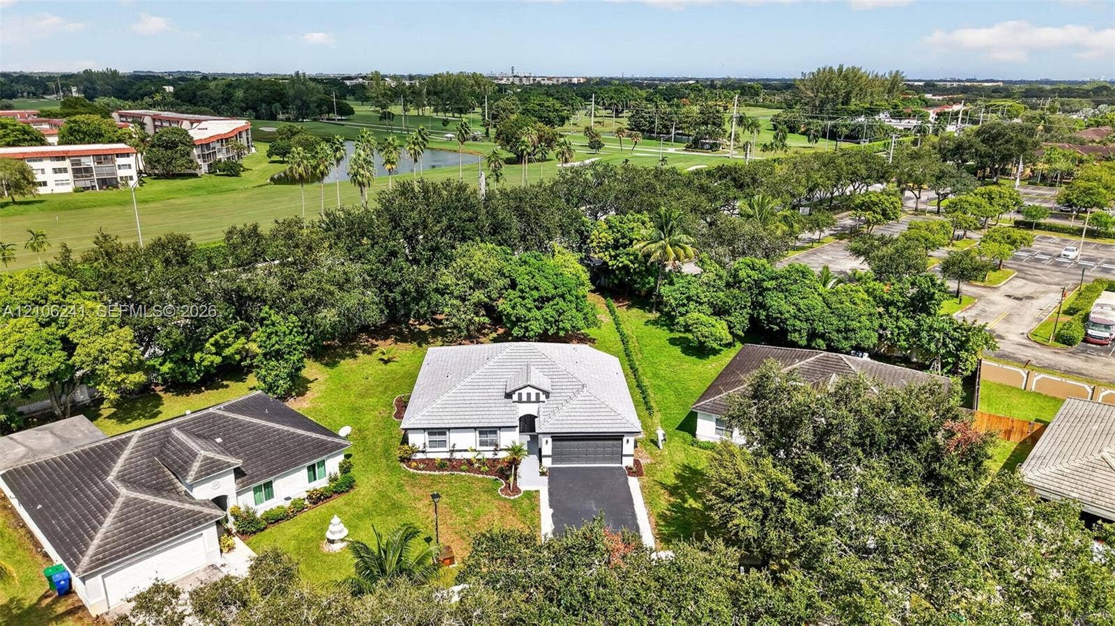 9407 SW 18th Street, Miramar, FL 33025 Single-story residence featuring a tile roof, light-toned exterior finish, attached two-car garage, asphalt driveway, and expansive lawn area