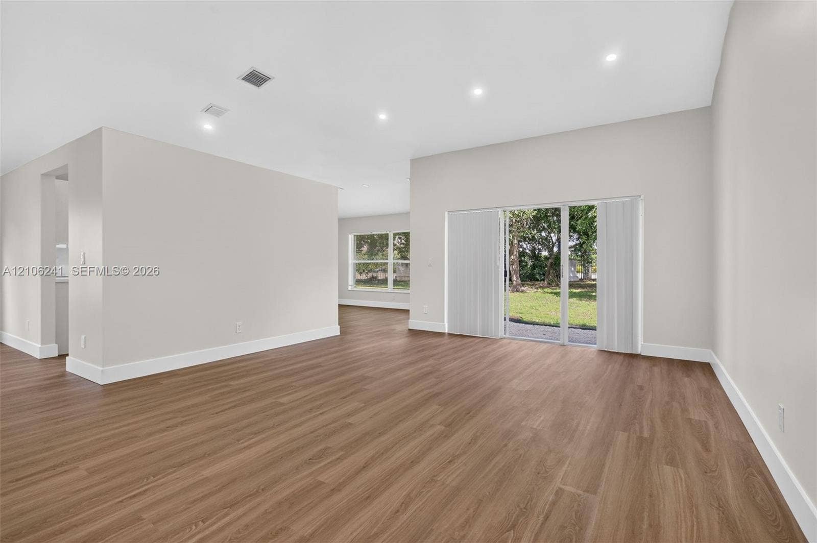 9407 SW 18th Street, Miramar, FL 33025 Open-concept living space featuring wood-finish flooring, recessed lighting, and a glass sliding door providing access to the exterior