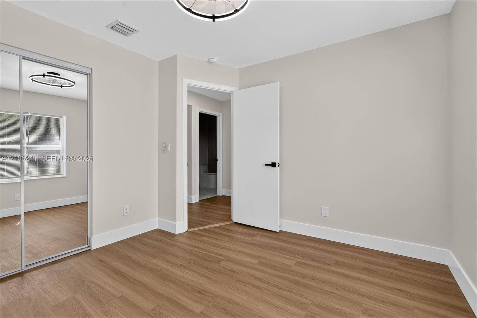 9407 SW 18th Street, Miramar, FL 33025 Neutral interior featuring wood-finish flooring, sliding mirror-panel closet doors, and matte black hardware