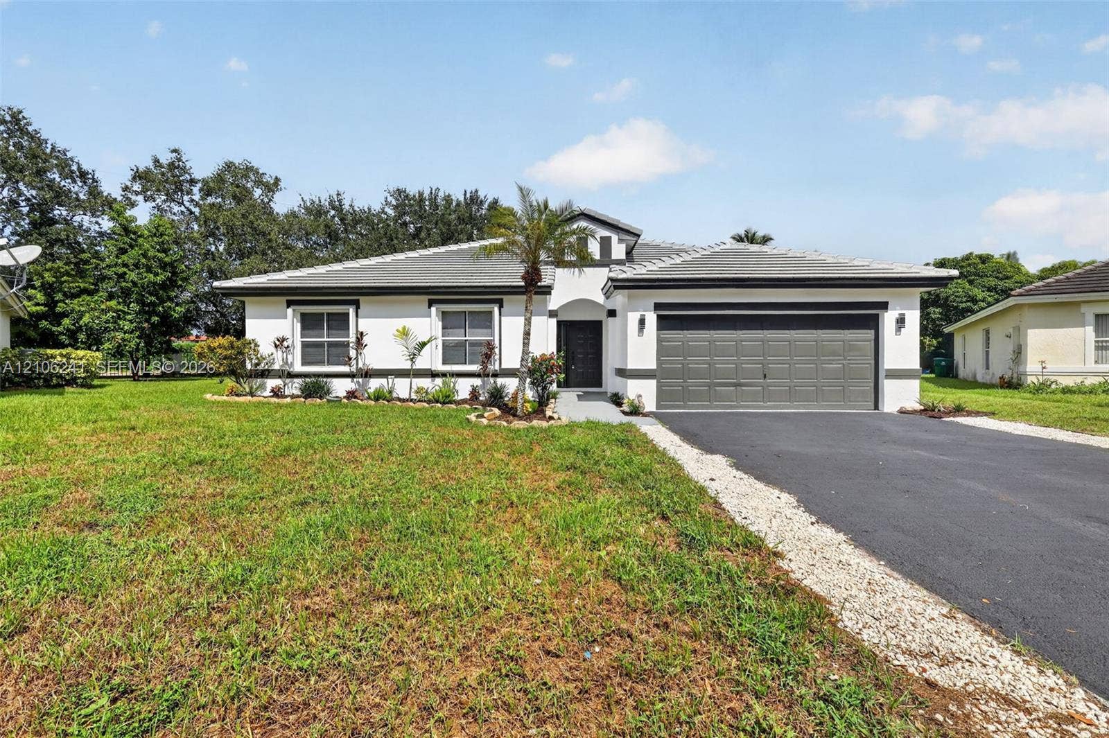 9407 SW 18th Street, Miramar, FL 33025 Single-story exterior featuring white stucco siding, a grey tile roof, a two-car garage, and a paved driveway
