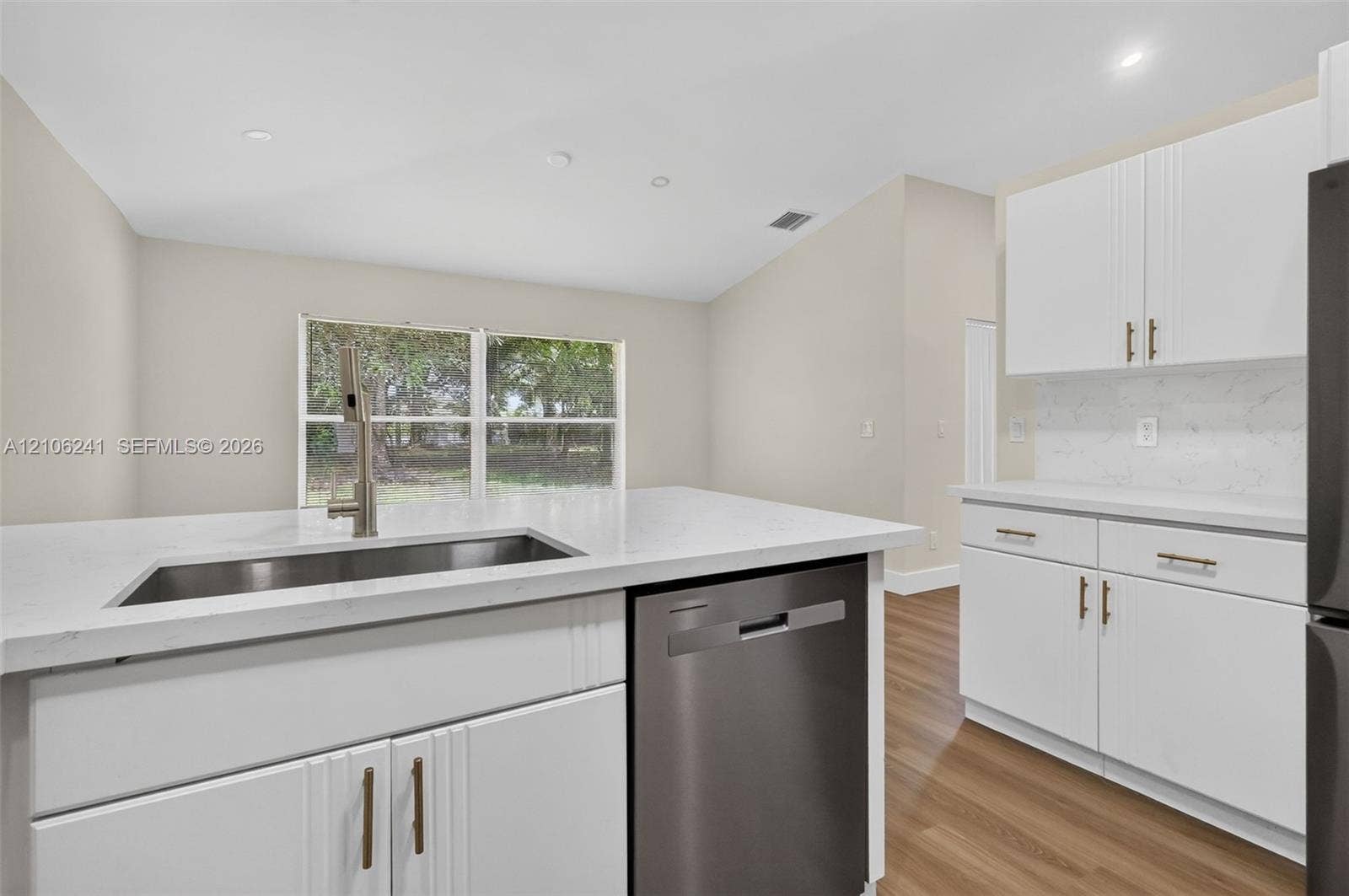 9407 SW 18th Street, Miramar, FL 33025 Kitchen featuring white shaker-style cabinetry, stone-surface countertops, recessed lighting, wood-finish flooring, and a stainless steel undermount sink with a high-arch faucet