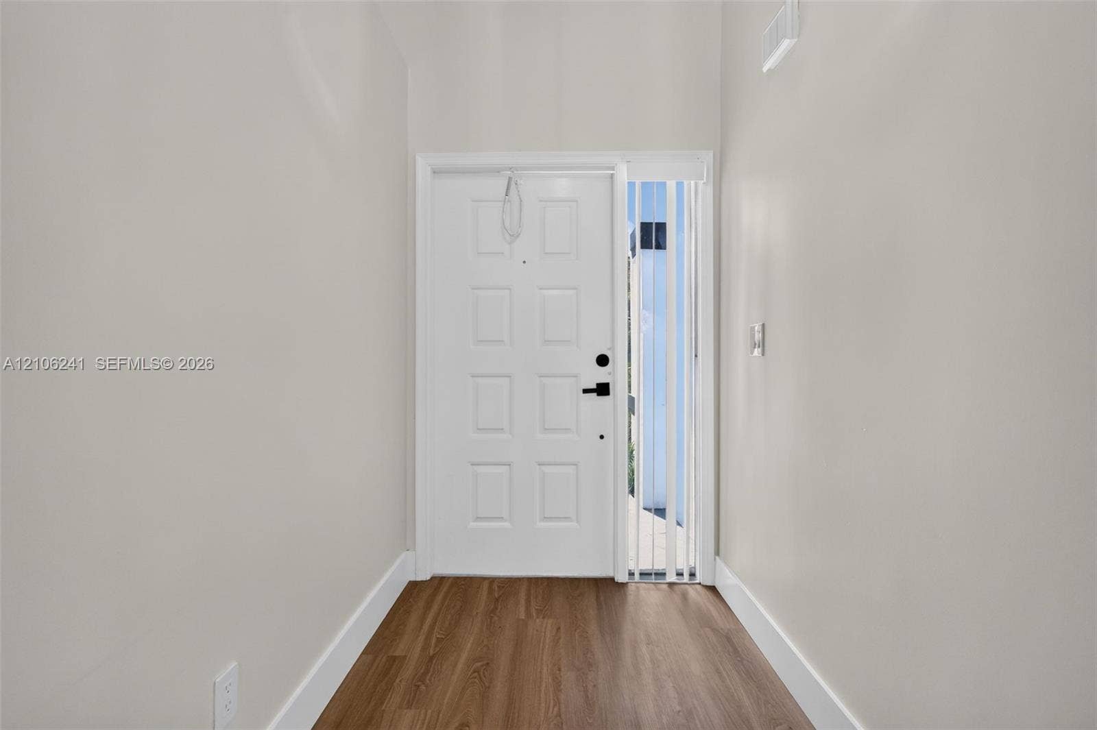9407 SW 18th Street, Miramar, FL 33025 Entryway featuring wood-finish flooring, a white paneled door with matte black hardware, and a vertical sidelight window with integrated blinds