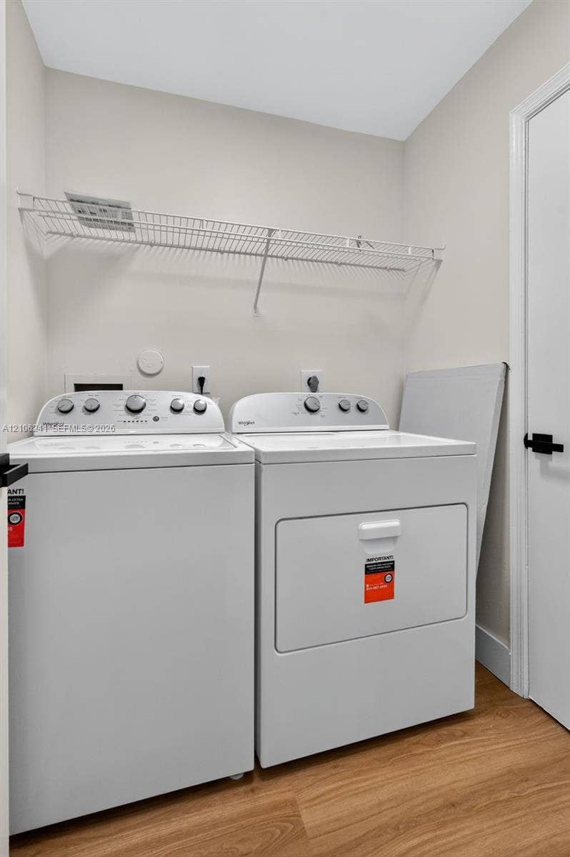 9407 SW 18th Street, Miramar, FL 33025 Laundry area featuring wood-finish flooring, white Whirlpool top-load appliances, and wall-mounted white wire shelving