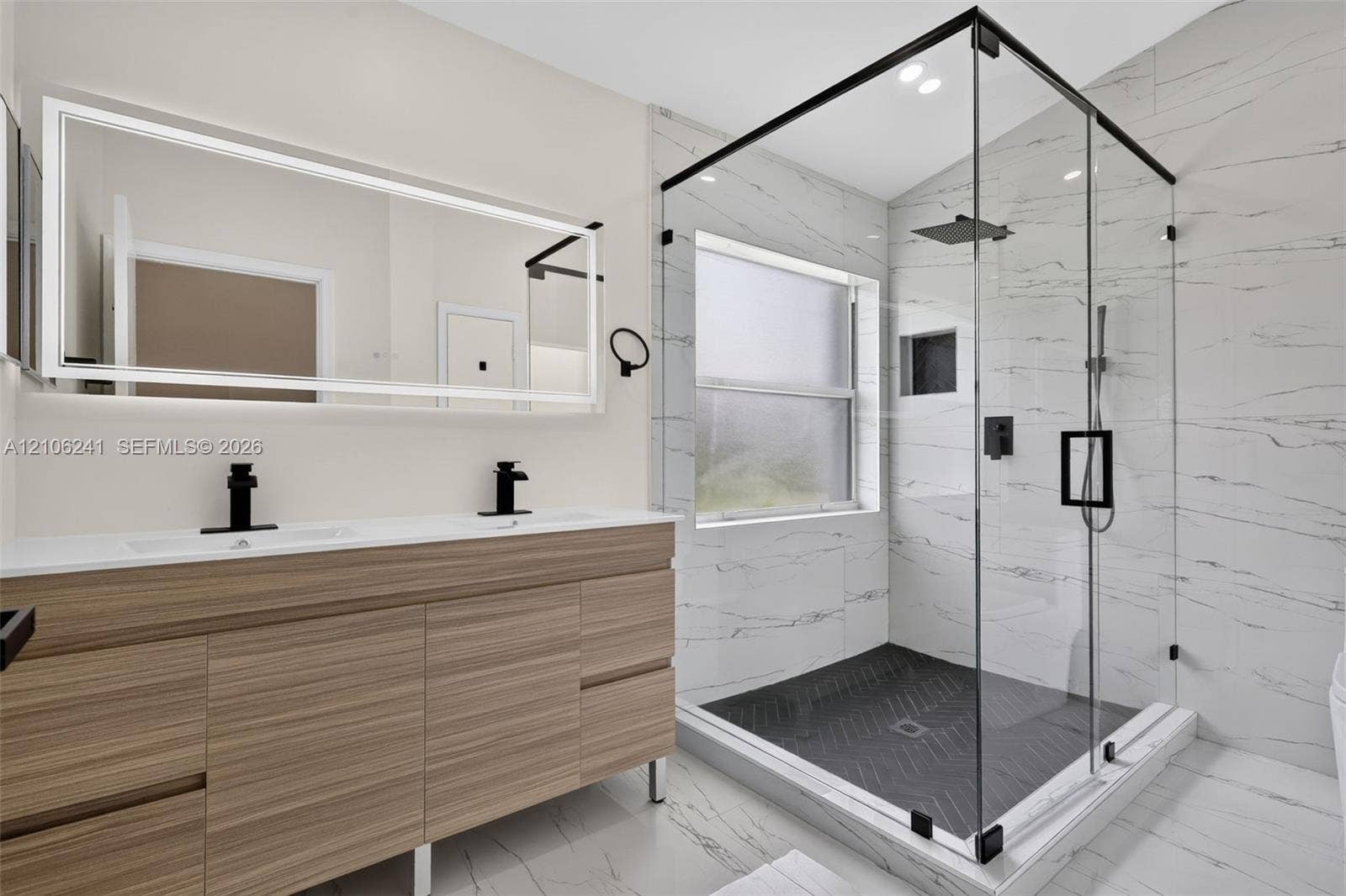 9407 SW 18th Street, Miramar, FL 33025 Double vanity with wood-finish cabinetry and quartz countertop, complemented by a large integrated LED-backlit mirror