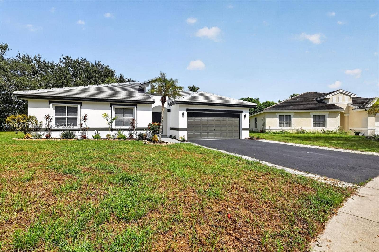 9407 SW 18th Street, Miramar, FL 33025 Single-story exterior featuring light-toned stucco, contrasting dark trim, a tiled roof, an attached two-car garage, and an asphalt driveway