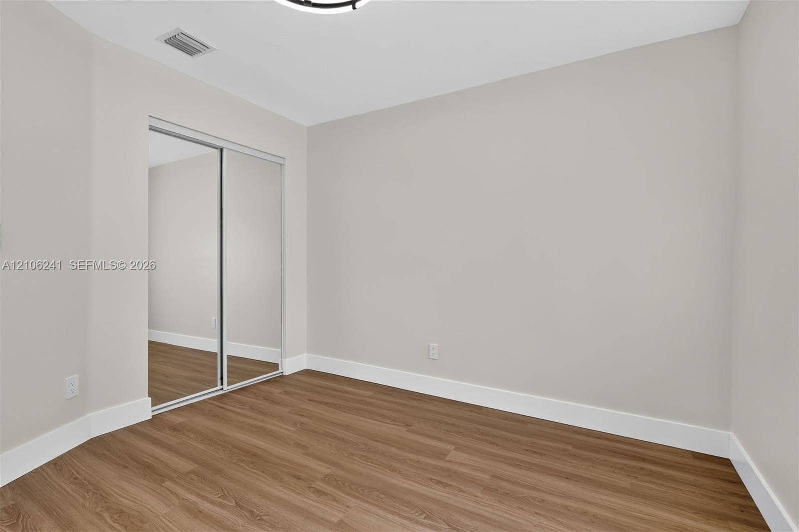 9407 SW 18th Street, Miramar, FL 33025 Interior space featuring wood-finish flooring, neutral wall paint, and closet with sliding mirrored doors