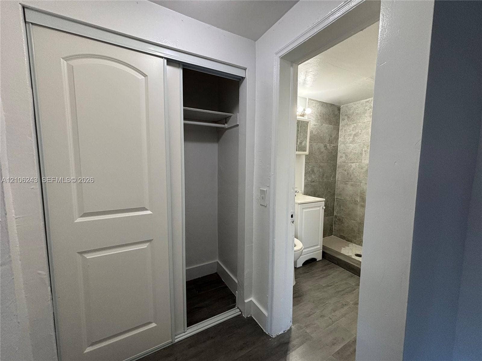 Sliding door closet featuring built-in shelving, wood-finish flooring, and white interior trim