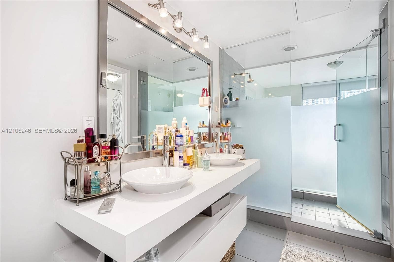 92 SW 3rd Street, #1511, Miami, Miami, FL 33130 Floating dual-vanity with rectangular vessel sinks, expansive wall-to-wall mirror, overhead track lighting, and a walk-in shower enclosed by frosted glass panels