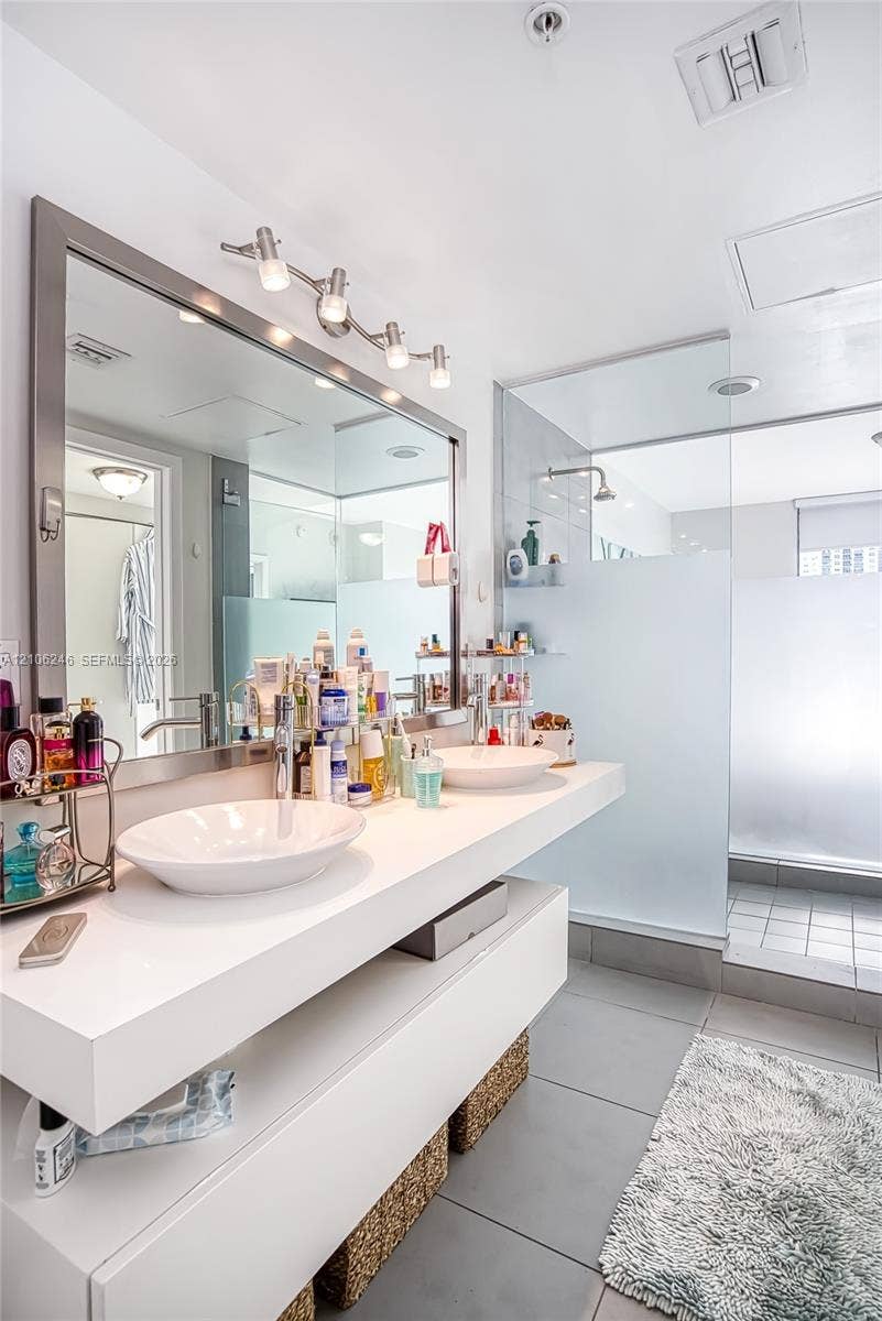 92 SW 3rd Street, #1511, Miami, Miami, FL 33130 Floating white vanity with dual vessel sinks, large framed vanity mirror, and walk-in glass-enclosed shower with frosted privacy glass and oversized tile flooring
