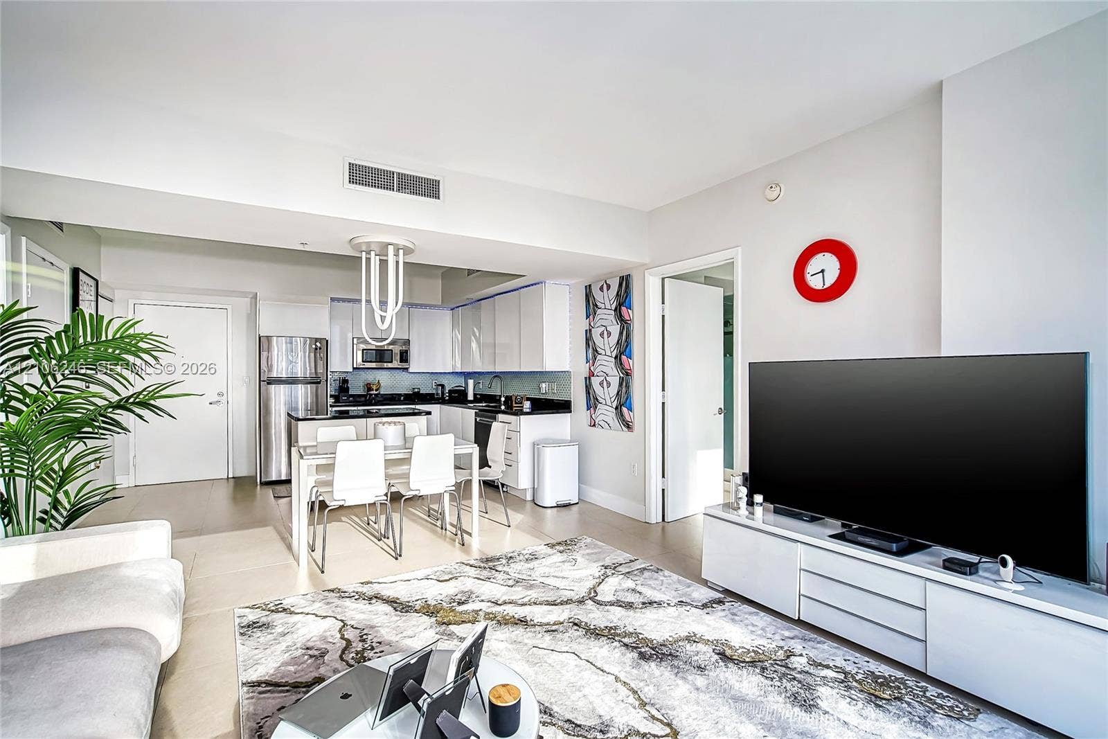 92 SW 3rd Street, #1511, Miami, Miami, FL 33130 Open-concept kitchen featuring high-gloss white cabinetry, contrasting dark countertops, stainless steel appliances, and a modern sculptural pendant light fixture