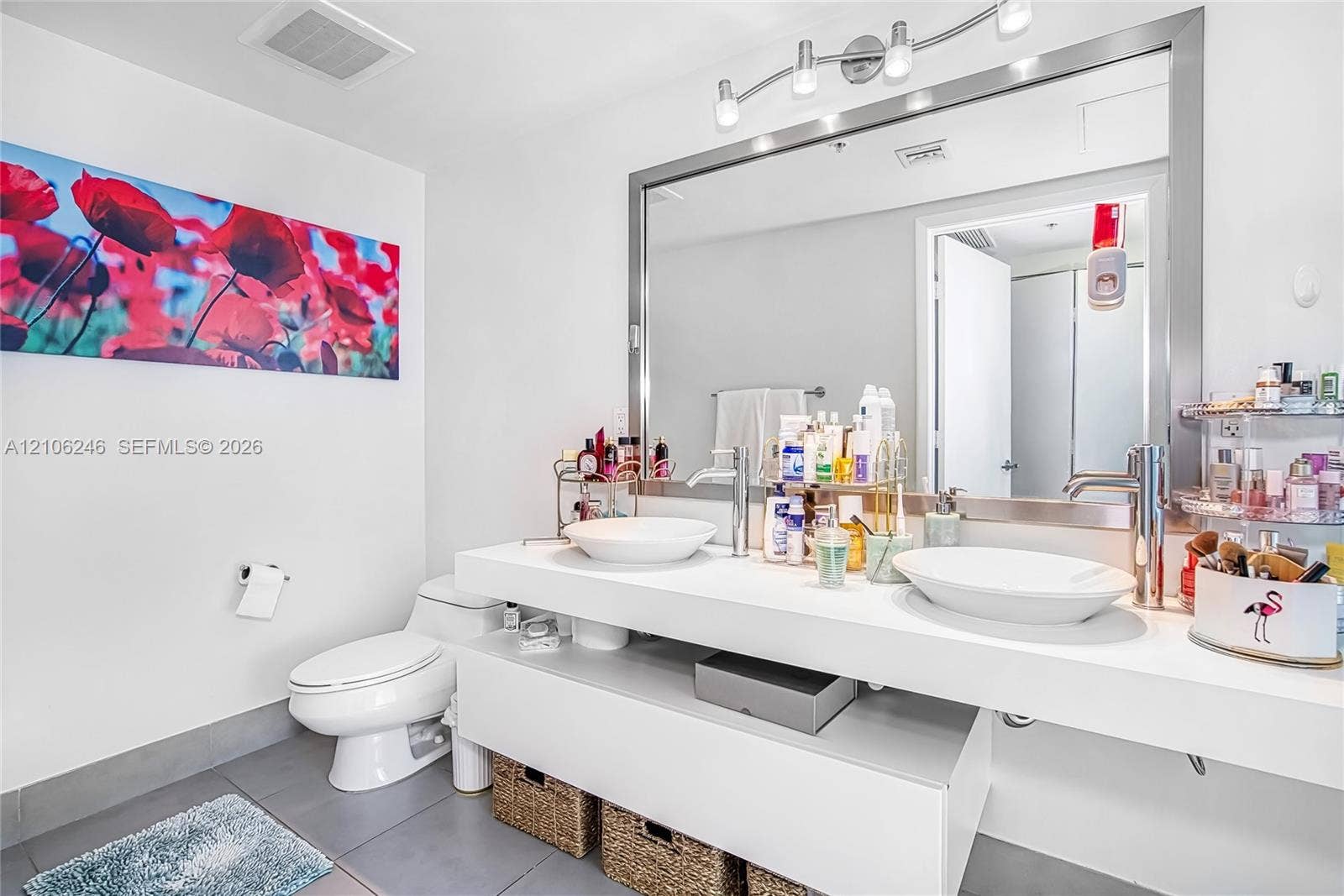 92 SW 3rd Street, #1511, Miami, Miami, FL 33130 Floating vanity featuring dual vessel sinks, chrome-finish faucets, a full-width mirror with a stainless steel frame, and multi-bulb vanity lighting