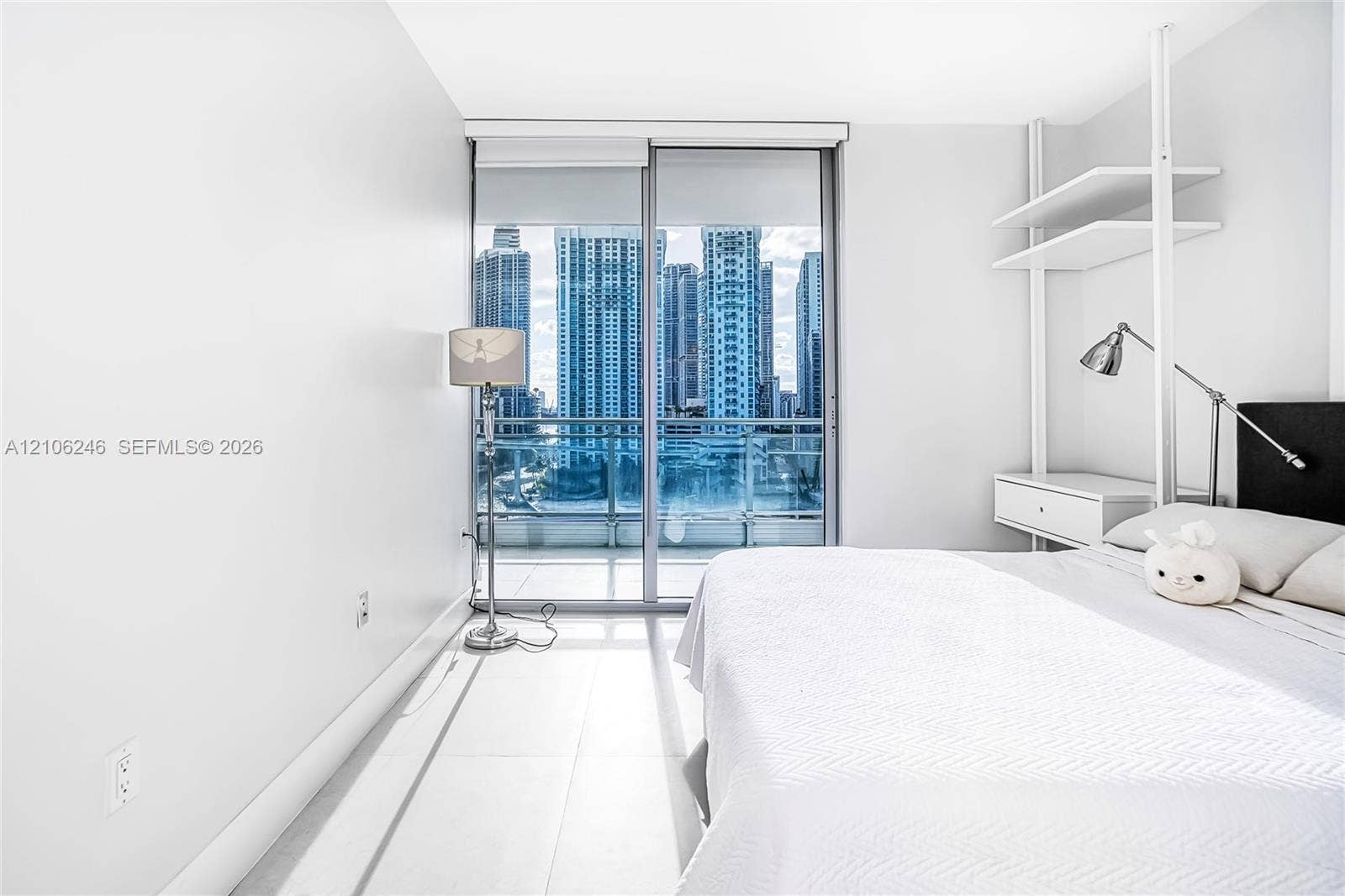 92 SW 3rd Street, #1511, Miami, Miami, FL 33130 Floor-to-ceiling glass sliding doors, large-format tile flooring, built-in shelving unit with an integrated drawer, and urban skyline backdrop