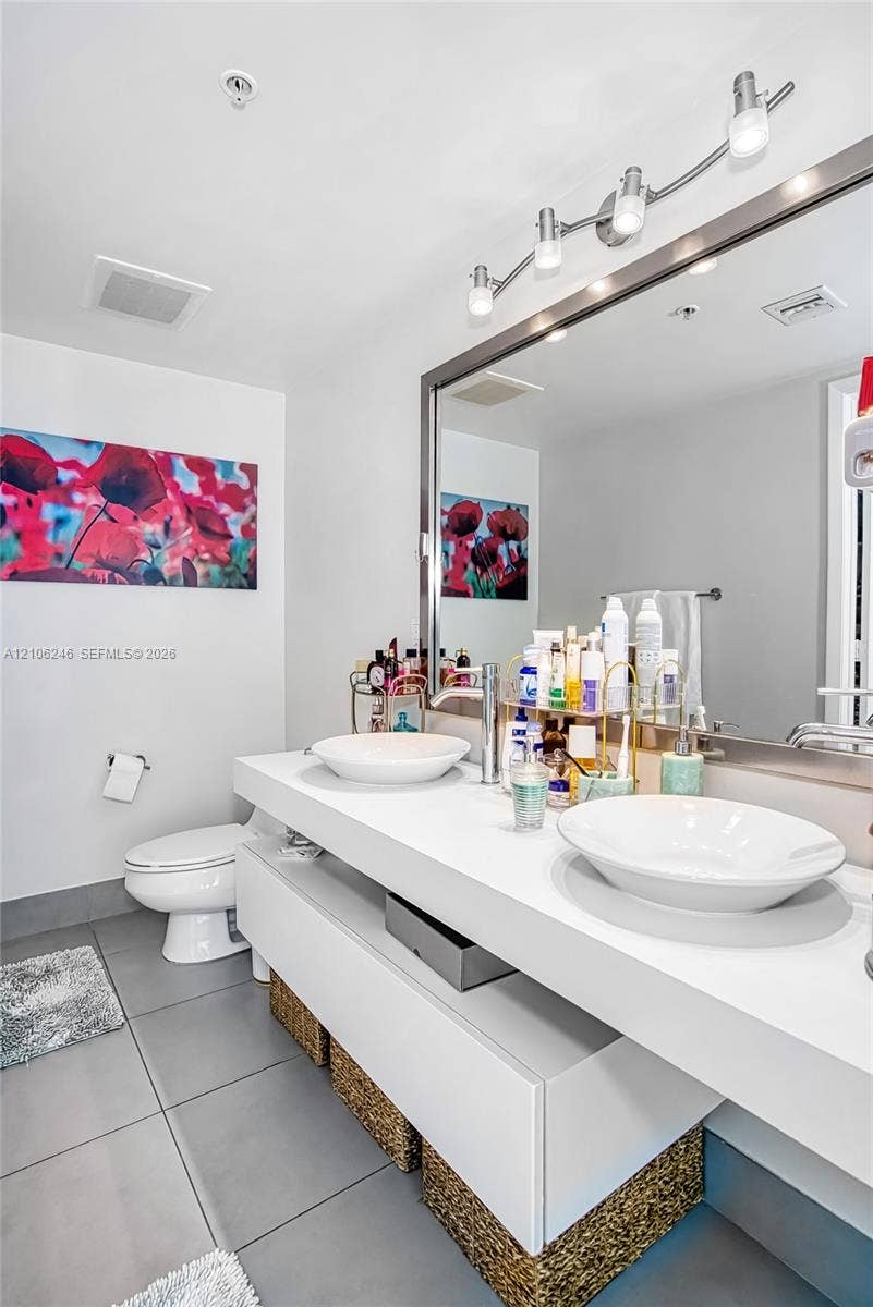 92 SW 3rd Street, #1511, Miami, Miami, FL 33130 Floating vanity featuring dual white vessel sinks, expansive countertop, large framed wall mirror, and modern multi-bulb overhead lighting fixture