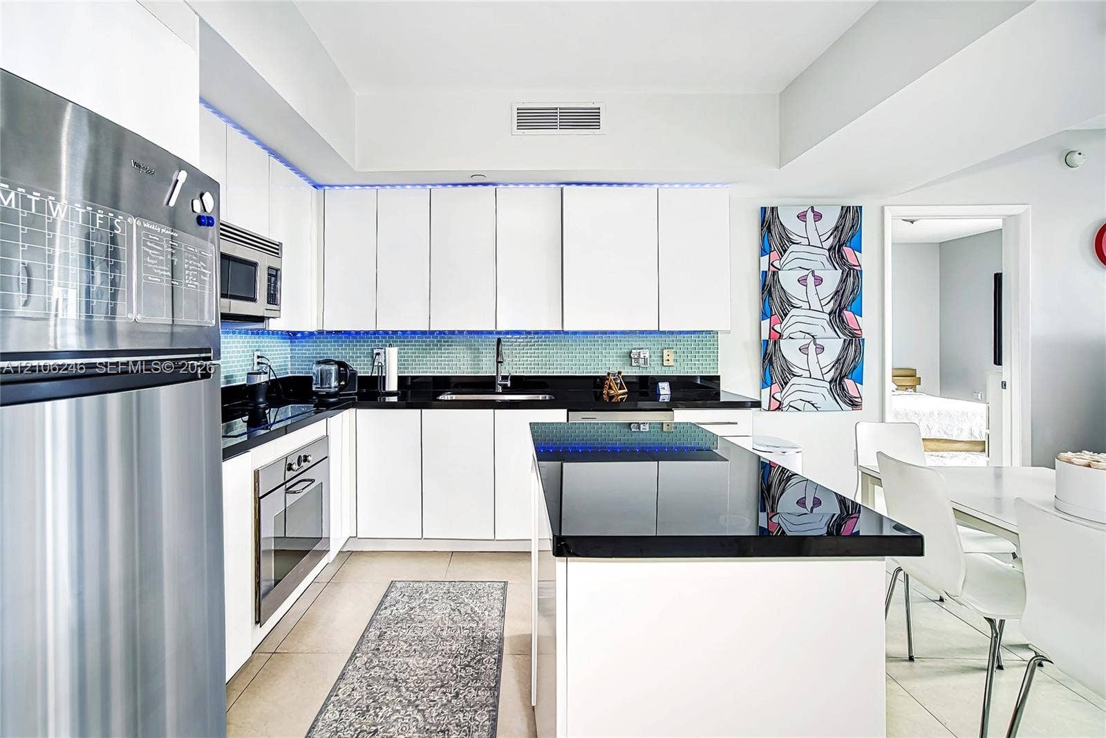 92 SW 3rd Street, #1511, Miami, Miami, FL 33130 Kitchen featuring white flat-panel cabinetry, a central island with a solid surface countertop, stainless steel appliances, and a tiled backsplash