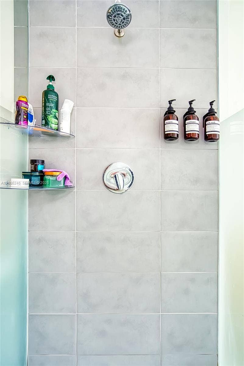 92 SW 3rd Street, #1511, Miami, Miami, FL 33130 Shower stall featuring large-format light gray tile, a chrome rainfall showerhead, a single-handle chrome pressure balance valve, and two integrated glass corner shelves