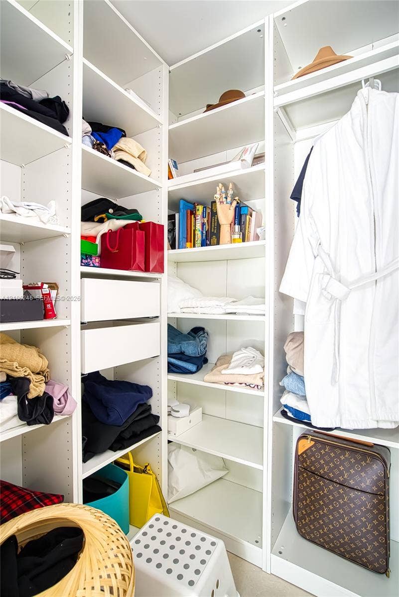 92 SW 3rd Street, #1511, Miami, Miami, FL 33130 Custom walk-in closet featuring white floor-to-ceiling built-in cabinetry, adjustable open shelving, and integrated pull-out drawers