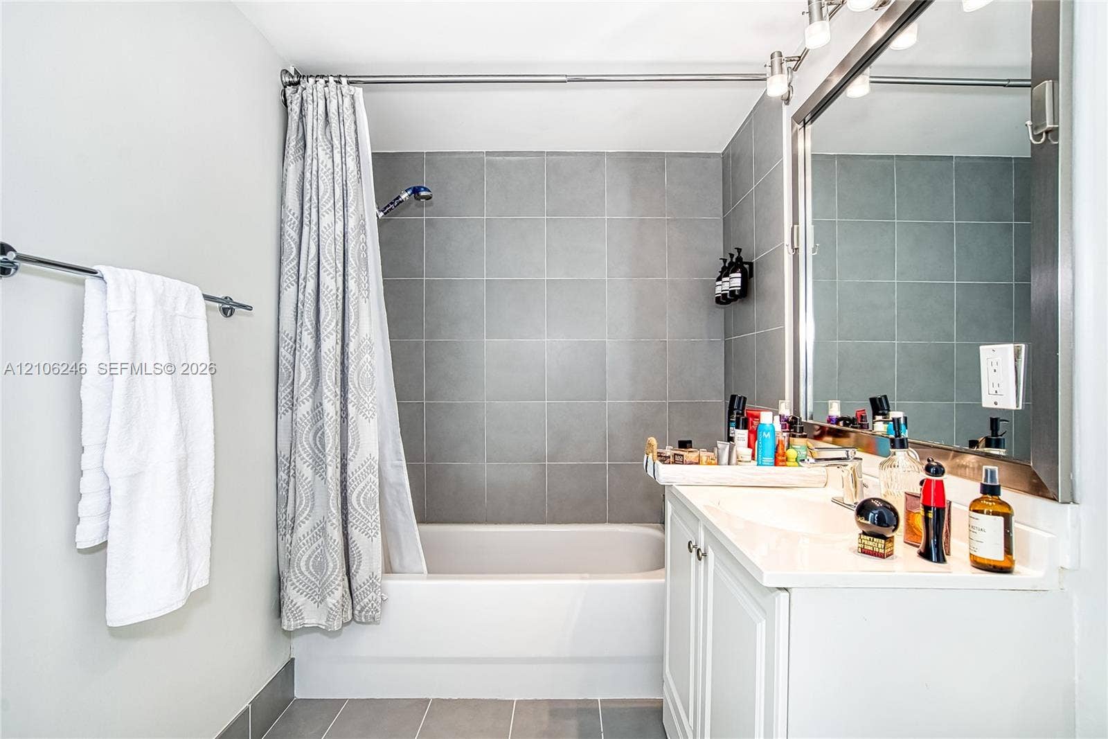 92 SW 3rd Street, #1511, Miami, Miami, FL 33130 Bathroom featuring a white vanity with a rectangular sink, wall-to-wall mirror, chrome light fixture, and a shower-tub combination with large-format grey tile surround