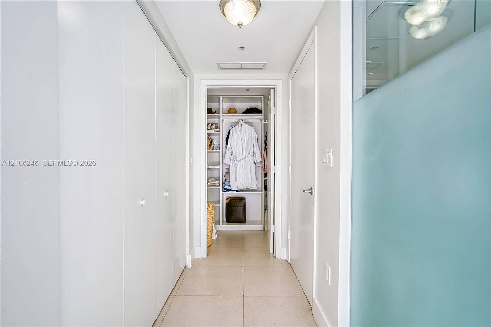 92 SW 3rd Street, #1511, Miami, Miami, FL 33130 Hallway featuring large-format tile flooring, ceiling-mounted light fixtures, extensive floor-to-ceiling built-in cabinetry, and a walk-in closet with integrated shelving