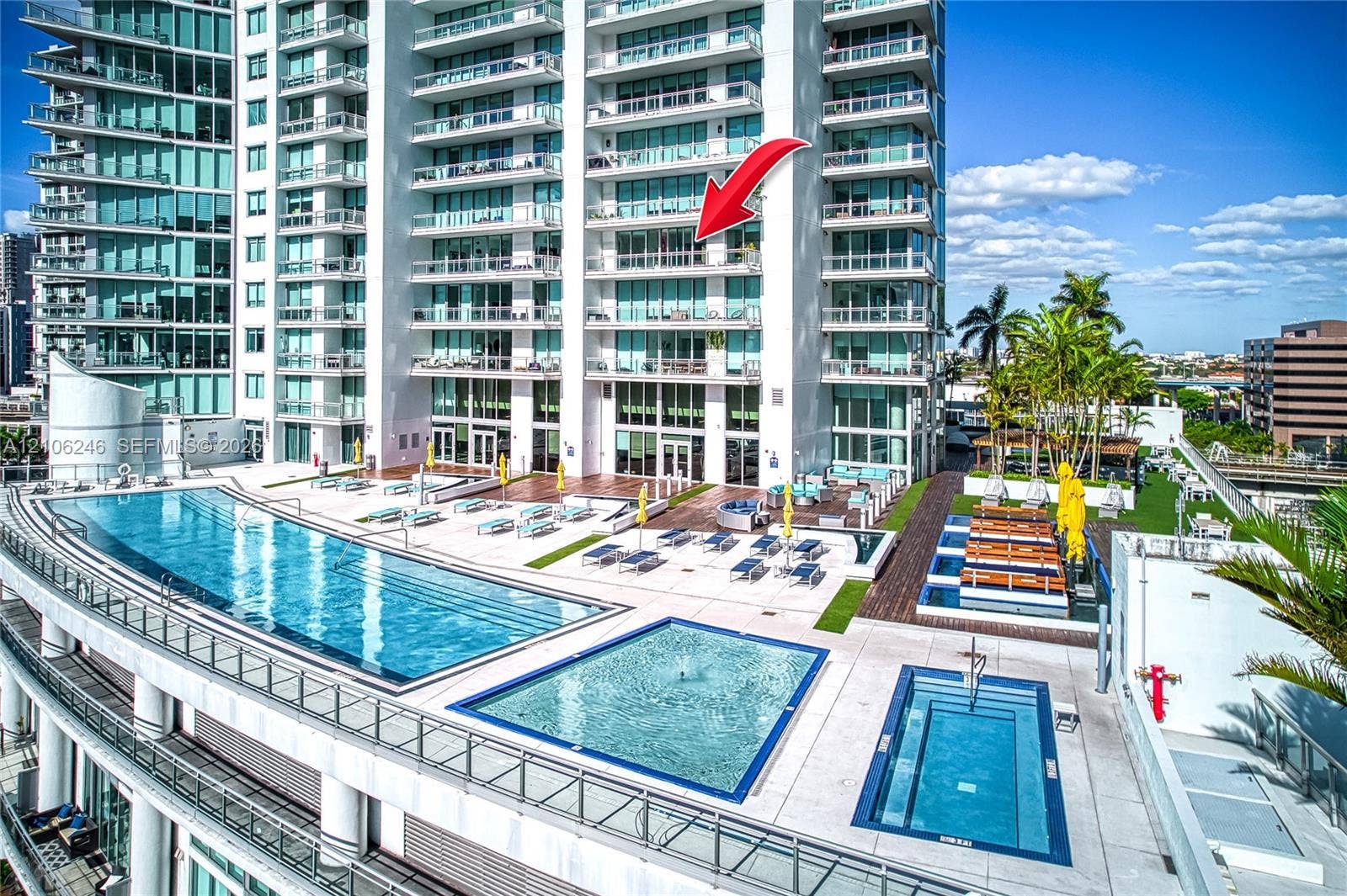 92 SW 3rd Street, #1511, Miami, Miami, FL 33130 High-rise condominium building featuring glass exterior wall panels and private balconies, complete with a multi-tier swimming pool deck, integrated water features, and manicured landscaping