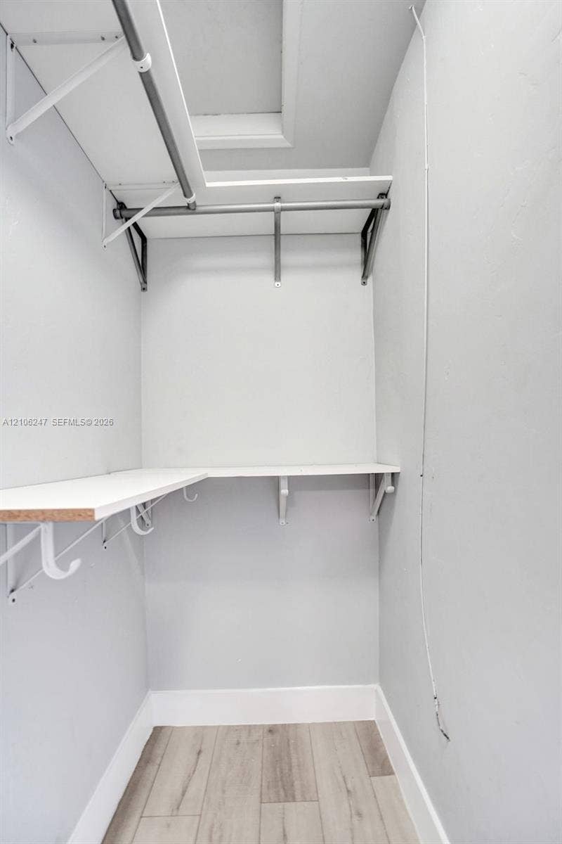 1037 N Victoria Park Road, #2, Fort Lauderdale, Fort Lauderdale, FL 33304 Walk-in closet featuring tiered white shelving, a metal hanging rod, and wood-finish flooring