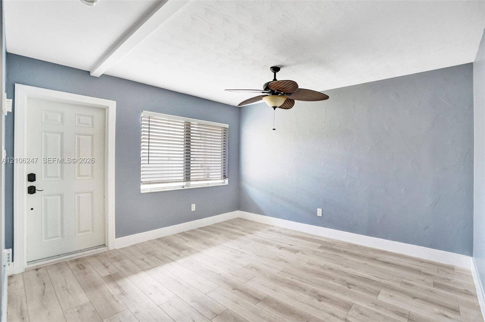 1037 N Victoria Park Road, #2, Fort Lauderdale, Fort Lauderdale, FL 33304 Interior room featuring wood-finish flooring, a textured wall finish, a multi-panel door with smart lock hardware, a window with horizontal blinds, and a central ceiling fan