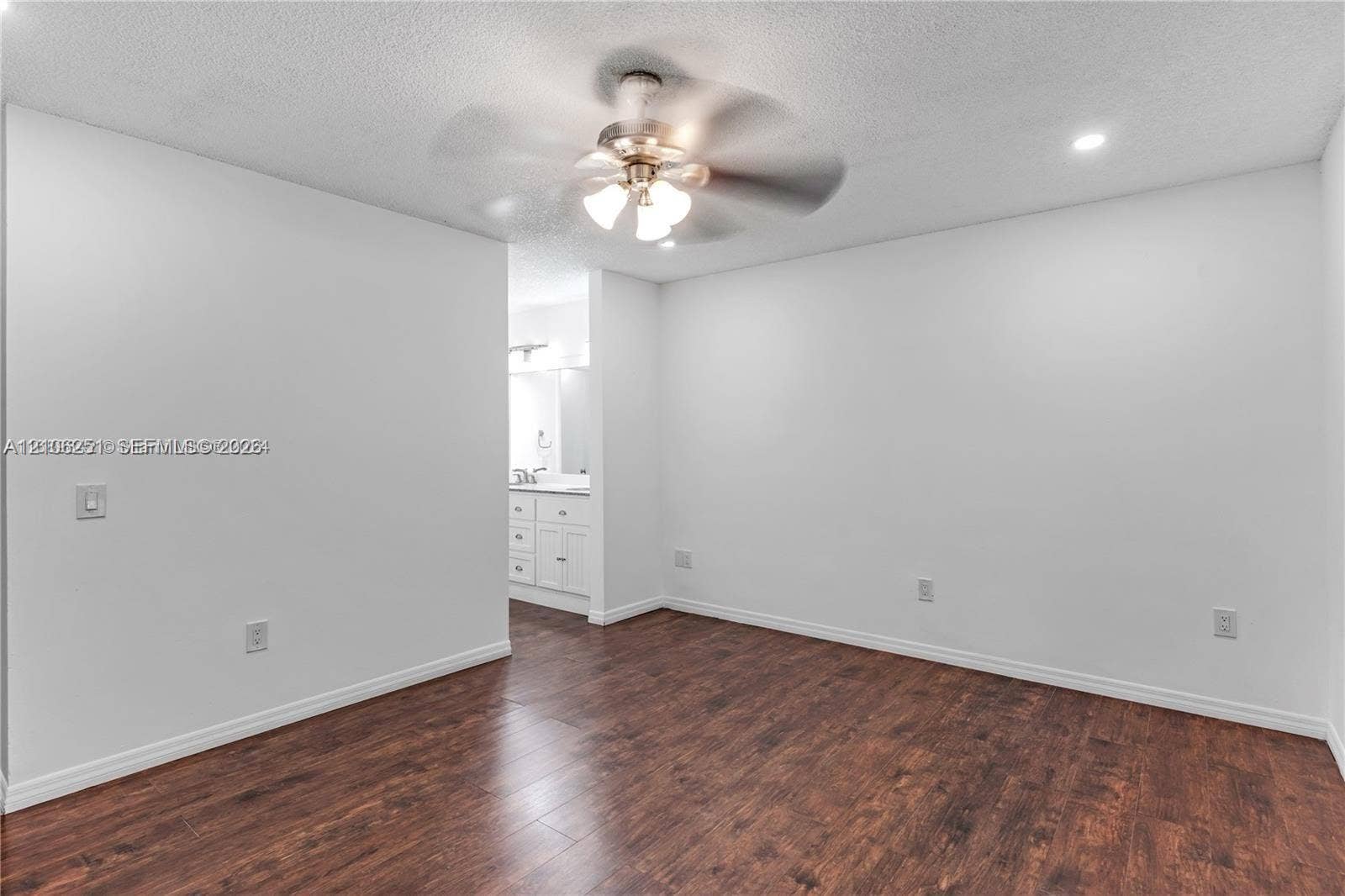 Neutral-toned interior room featuring wood-finish flooring, a ceiling fan with integrated lighting, and recessed ceiling lighting