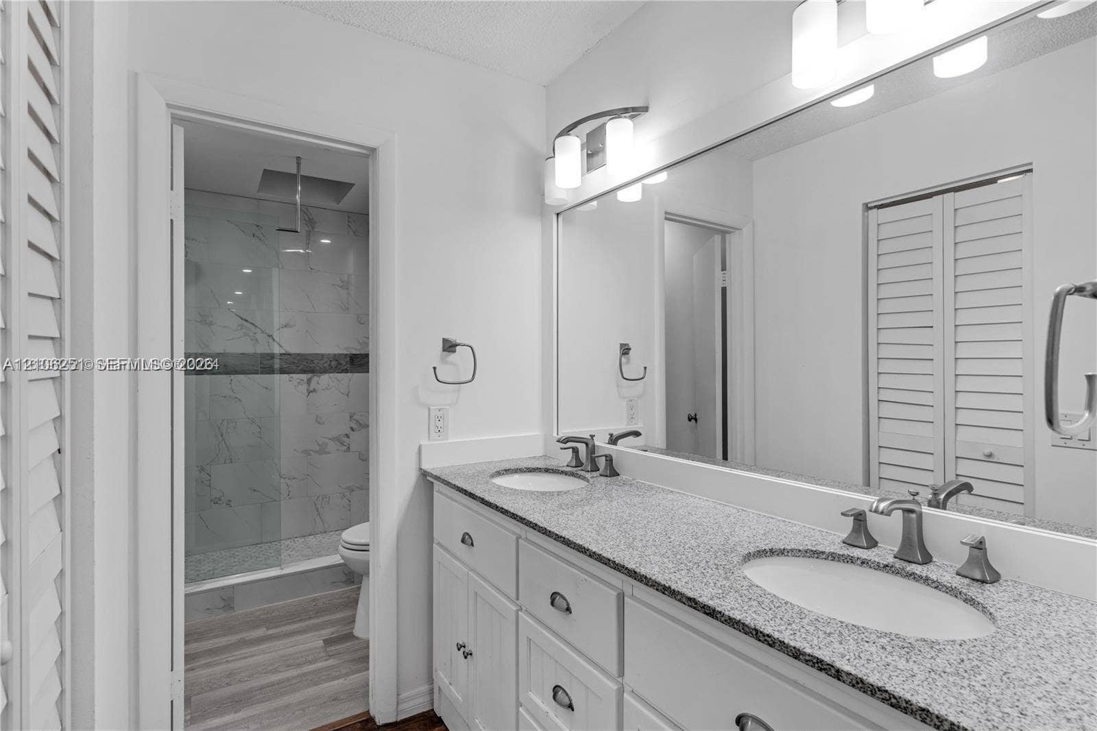 Double vanity featuring a speckled countertop, integrated dual sinks, and brushed metallic hardware