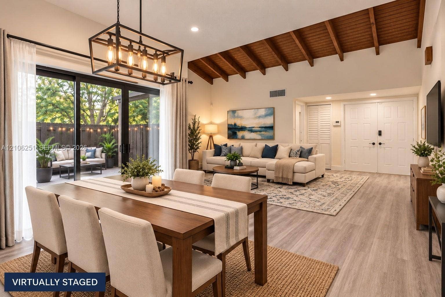 Vaulted ceilings with exposed wooden beams, wood-finish flooring, a matte black geometric chandelier, and floor-to-ceiling sliding glass doors