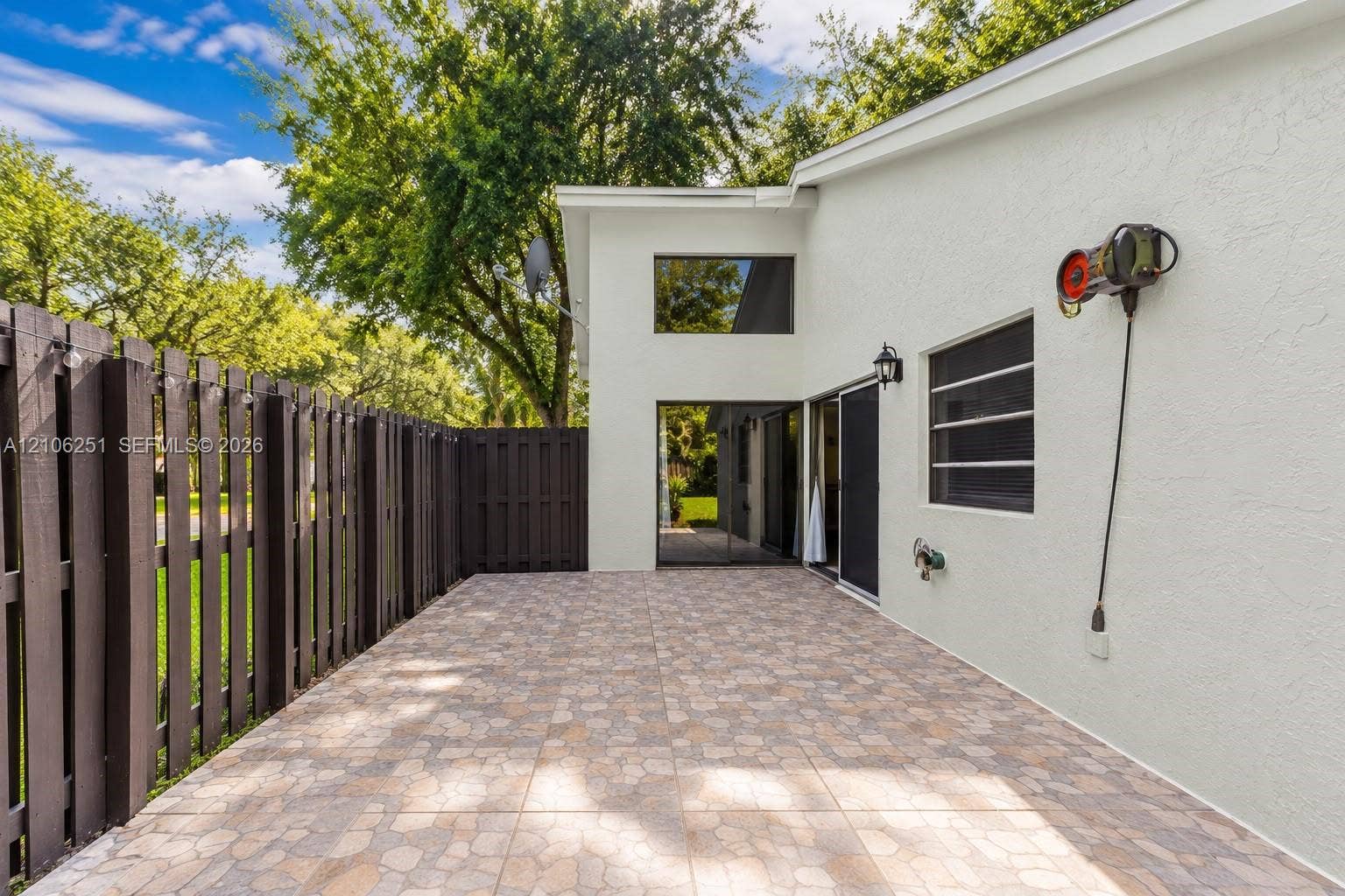 Exterior patio featuring patterned tile flooring, a privacy fence, and integrated wall-mounted lighting