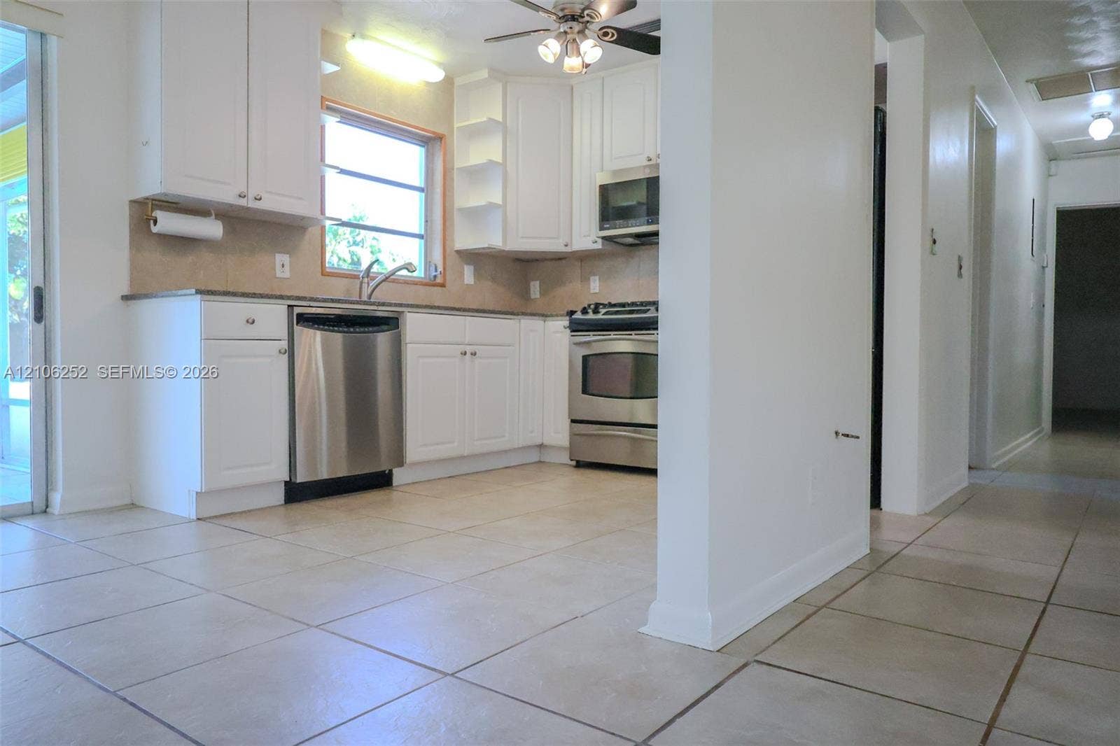 225 E Ilex Drive, Lake Park, Lake Park, FL 33403 Kitchen featuring white cabinetry, stone-finish countertops, tile flooring, and stainless steel appliances including a gas range and built-in microwave